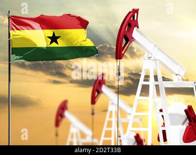 Oil rigs against the backdrop of the colorful sky and a flagpole with the flag of Ghana. The concept of oil production, minerals, development of new d Stock Photo