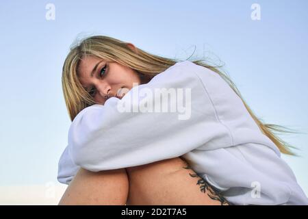 Side view of serene female traveler sitting and looking at camera during summer adventure Stock Photo