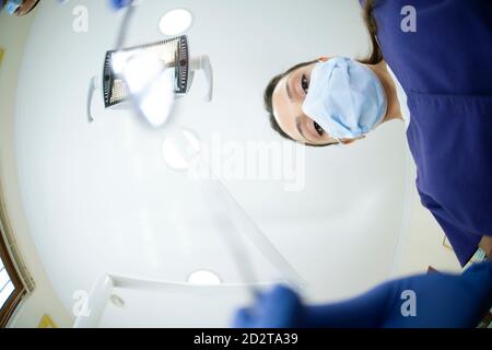 From below female Asian dentist holding mirror while working in modern office in clinic Stock Photo