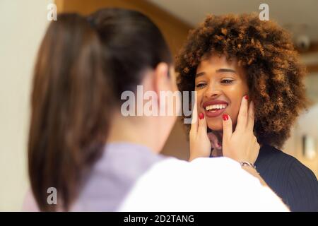 anonymous Woman dentist checking teeth of African American lady in dental clinic Stock Photo