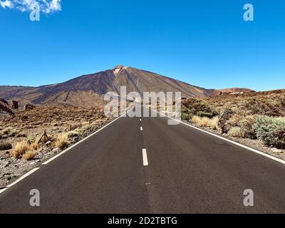 Amazing perspective view of asphalt roadway leading to Mount Teide under blue sky on sunny day in Tenerife Stock Photo