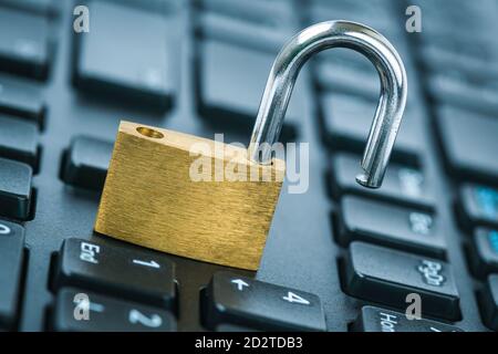 Computer security concept. Unlocked padlock on laptop keyboard. Open security lock on computer keyboard - computer security breach concept. Stock Photo