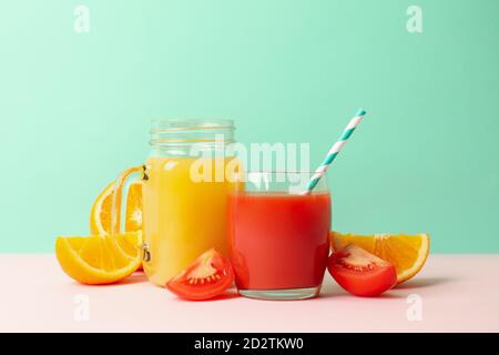 Jars with tomato and orange juices against mint background Stock Photo