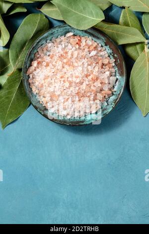 A close-up of pink Himalayan salt with bay leaves, shot from the top with a place for text on a blue background Stock Photo