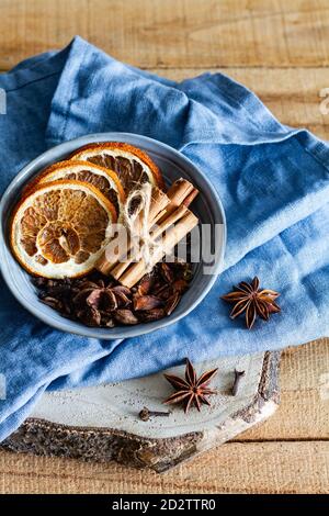 High angle of bowl with aromatic cinnamon sticks and dried oranges arranged on table with star anise and cloves Stock Photo