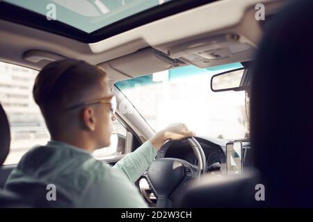 Back view of unrecognizable focused male driver driving a luxury car Stock Photo