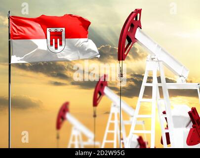 Oil rigs against the backdrop of the colorful sky and a flagpole with the flag of Vorarlberg. The concept of oil production, minerals, development of Stock Photo