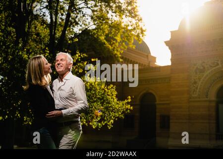 Side view of tender mature couple hugging in park in summer while enjoying sunny day together Stock Photo