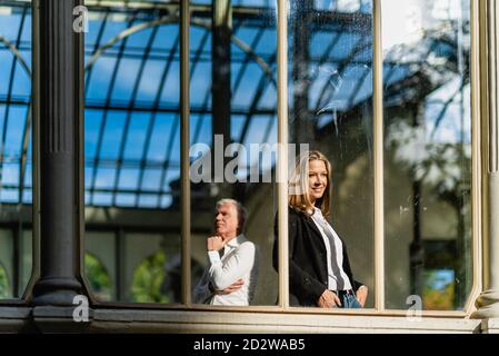 Thoughtful man and Woman standing in historic glass building during stroll in city and looking away Stock Photo