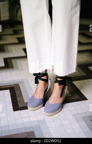 Side view of anonymous crop female wearing wedge sandals and trendy jeans standing in modern flat Stock Photo