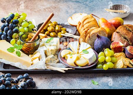 Cheese plate served with fruits, honey and snacks. Assorted cheese background. Stock Photo