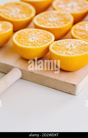 Closeup of halves of ripe juicy oranges on wooden chopping board in studio on white background Stock Photo