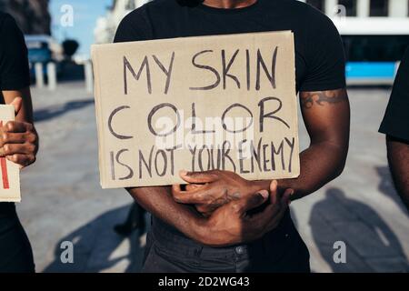 anonymous man protesting at a rally for racial equality holding a poster against racism. Black Lives Matter. Stock Photo