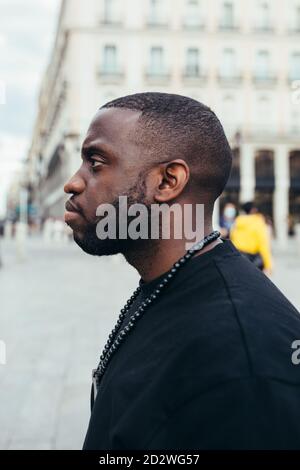 Side view portrait of serious black man looking away in urban scenery Stock Photo