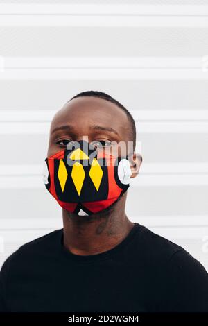 Closeup portrait of african american man wearing a colorful mask. He is looking at camera with serious expression Stock Photo