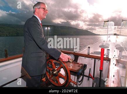 Steady as she goes, Prime Minister John Major takes the wheel of the Pleasure boat the Coniston Gondola, during his trip around Lake Coniston in the Lake District today (Fri). WPA Rota Picture Stock Photo