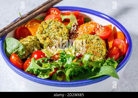 Falafel salad with baked vegetables and tomatoes in a white bowl. Israeli street food concept. Stock Photo