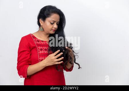 Portrait of Indian woman with fingers in her long hair, dark hair, white backdrop, indoor studio shot, copy space area. Stock Photo