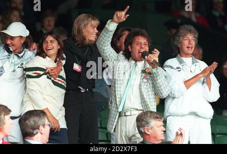 Sir Cliff Richard leads the community singing on Centre Court at Wimbledon this afternoon (Wednesday) after rain stoppped play. Right is Virginia Wade, the last British female to win the singles in 1977. Photo by Adam Butler/PA. Stock Photo