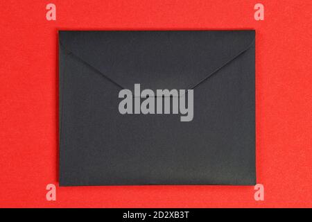 Black closed cardboard envelope. Isolated on red, clipping path included Stock Photo