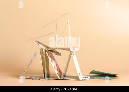 Crashed house of cards. Falling cards on beige background Stock Photo