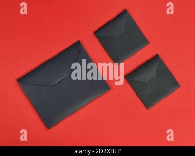 Three black cardboard envelope on red background. Top view, flat lay Stock Photo