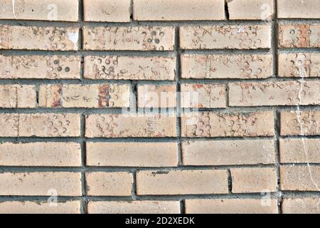 The texture of old broken bricks. Dirty brick walls from damage and smeared with paint. Traces of damage on the background of the wall of blocks. Stock Photo