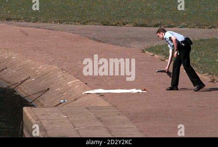 A policeman lays some flowers beside the lake at Fairlands Valley Park in Stevenage, Hertfordshire today (Friday) where the body of 5-year-old Martin Hollis was found yesterday evening. Martin, who lived in the neighbouring town of Letchworth, was on a day out with nine other children from a social services family centre when he died. The two workers and a volunteer from the Noel Family Centre in Letchworth who supervised the day-trip were said to be distraught over the incident. See PA story POLICE Boy. Photo by Sean Dempsey/PA. Stock Photo