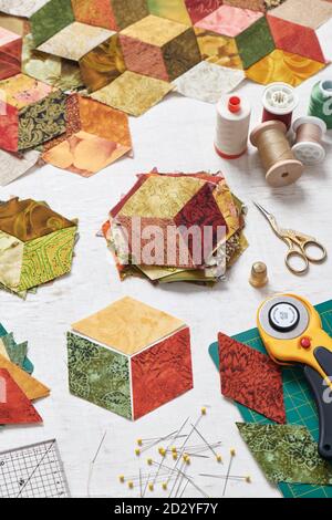 Fragment of tumbling blocks quilt, accessories for quilting on a white surface Stock Photo