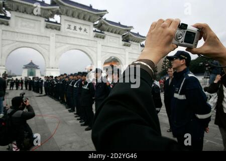 People take pictures of the main gate of the Taiwan Democracy Memorial Hall as police officers stand guard in Taipei December 5, 2007. Taiwan's Ministry of Education announced plans to remove the plaque that adorns the hall's main gate and replace it with one that reads 'Liberty Square'. The hall was previously known as the Chiang Kai-shek Memorial Hall and the ministry said the change was being done to reflect the hall's new name.   REUTERS/Pichi Chuang (TAIWAN)