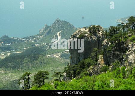 Mountain view of the black sea coast. Dawn in Crimea and fog in the mountains. The oil platform is far out to sea. Pine forest on the rocks in Russia. Stock Photo
