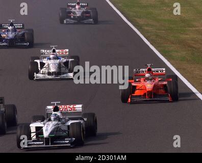 German F1 driver Michael Schumacher of Ferrari (R) attempts to overtake other cars after the start of the Formula One Japanese Grand Prix in Suzuka 01 November. Michael Schumacher, competing four-point behind of Mika Hakkinen of Finland, stalled his engine and started the race at the back of the grid.   (ELECTRONIC IMAGE)  PA NEWS PHOTO Stock Photo