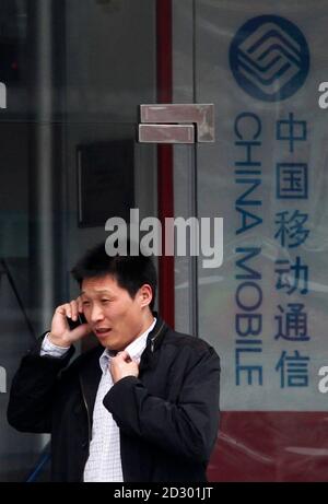 A man talks on his mobile phone in front of a China Mobile shop in central Beijing April 20, 2010. China Mobile, the world's largest carrier with more than 500 million subscribers, will post first-quarter results on Tuesday, with analysts expecting them to post a 7 percent profit gain to around 27 billion yuan ($3.9 billion).      REUTERS/David Gray      (CHINA - Tags: BUSINESS)