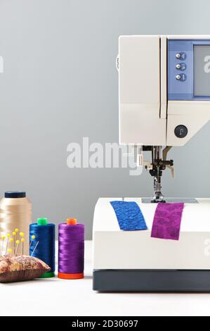 Spools of threads next to sewing machine on gray background Stock Photo