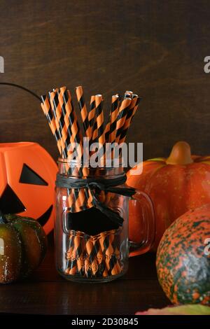 Preparation for Halloween party with pumpkins, drinking straws for drinks on dark wooden background. Stock Photo