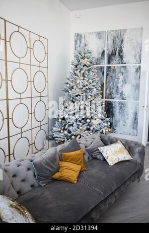 https://l450v.alamy.com/450v/2d31394/stylish-room-with-a-large-snow-covered-blue-spruce-christmas-decorated-with-a-garland-golden-balls-flowers-pine-cone-fashionable-sofa-with-orange-2d31394.jpg