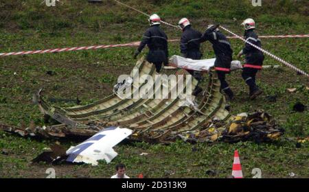 Emergency services carry body bags through the wreckage of the aircraft ...