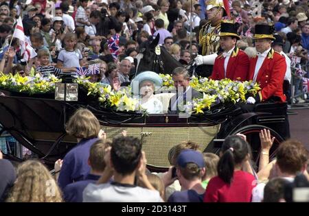 The Queen Mother with the Prince of Wales, in a horse drawn carriage, waves to the crowds gathered on The Mall, as she arrives at Buckingham Palace, London, for her 100th birthday celebrations. Stock Photo