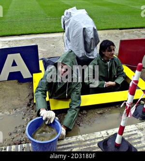 A television crew use a bucket to empty their camera pit of rain water as they prepare to cover the World Cup qualifier football match between England and Germany at London's Wembley Stadium. Stock Photo
