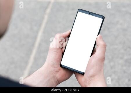 Image of mans hand holding modern black mobile phone with blank white screen. Man using mobile smart phone, close up. Stock Photo