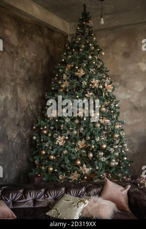 Magic Christmas card. Textured dark loft with a large green Christmas tree, fashionable toys, decorations, garlands. Presents lie by the old vintage Stock Photo