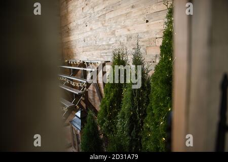 Rustic style room. A wooden staircase, a wall decorated with a garland of led lamps, there are Christmas trees, a juniper. large lanterns for candles. Stock Photo