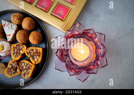 Assorted Indian sweets or Mithai, Rava laddoo, Besan laddu, dry fruits sweets in a black plate along with Happy Diwali chocolates for Diwali festival. Stock Photo