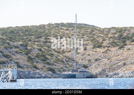 A metal catamaran anchored right beside the solarwind power production on a floatable construction at Iraklia,Cyclades,Greece Stock Photo