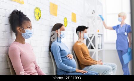 Multiracial Coronavirus Patients Sitting In Queue Waiting Appointment In Hospital Stock Photo