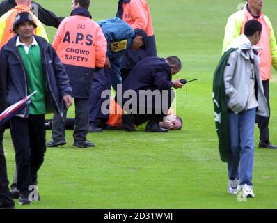 A Safety Steward lies injured after a pitch invasion stopped the England and Pakistan cricket match, during the NatWest Series Triangular One Day game at Headingley, Leeds 2001. Stock Photo