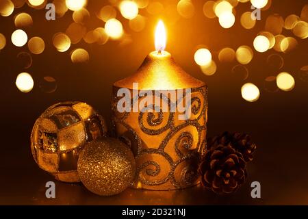 Christmas decoration with burning candles on a dark background. Christmas ornaments over dark golden background with lights. Stock Photo