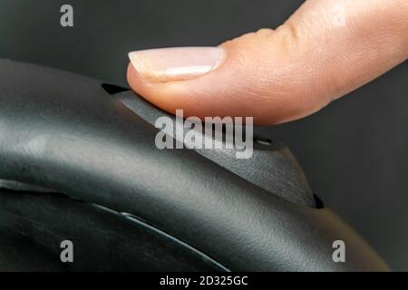 Female finger presses the button to turn on the black electric kettle, macro Stock Photo
