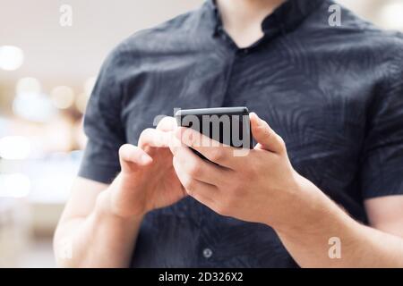 Man using mobile smart phone, close up. Picture of young man using a mobile smart phone and smiling. Stock Photo