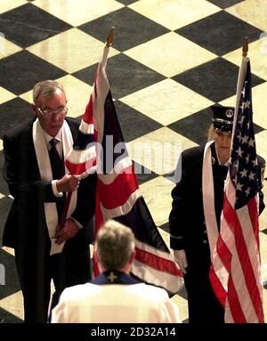 The Union Jack flag, left, carried by Detective Constable Ron Cuthbertson and the American flag carried by Lieutenant Amy Monroe from the New York Fire Department, are received by the Dean of Westminster, Wesley Carr, cente.  *... in London's Westminster Abbey at the beginning of a service for the British victims of the terrorist attacks on the United States on Tuesday Sept. 11, 2001. Stock Photo